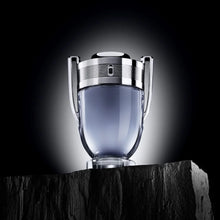 Показана е бутилка на мъжката тоалетна вода Rabanne Invictus EDT от Paco Rabanne с декоративен капак и елегантен дизайн.