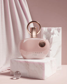 Една жена държи бутилка Afnan Supremacy Pink EDP парфюмна вода за жени с розов дизайн и флорални нотки.